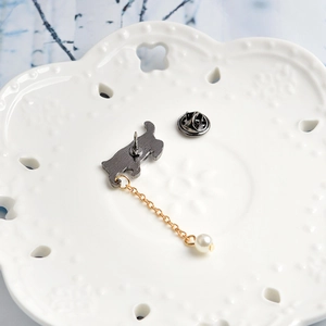 Close-up of cat brooch back showing needle pin, butterfly clutch, and gold chain with pearl