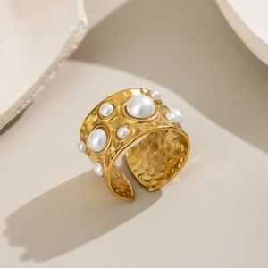 Bague ouverte dorée avec perles blanches et texture métallique martelée au soleil
