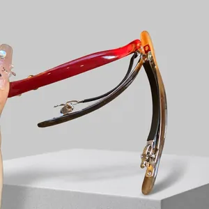 Close-up of acetate spring hair clips in red, tortoiseshell, and amber on wood