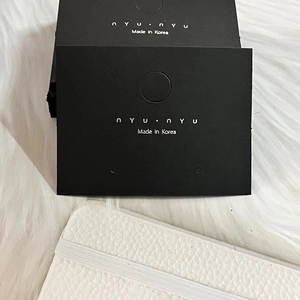 Detail of black paper earring display cards with white lettering on soft white plush background