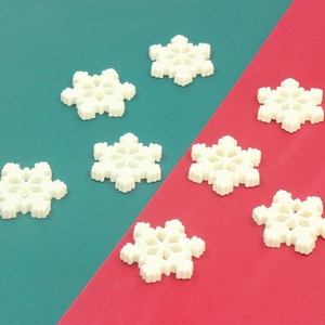 Detailed view of eight white resin snowflake charms for DIY crafts on festive background