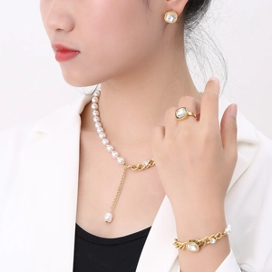 Elegant gold-tone jewelry set with square gemstones and pearls on a professional model