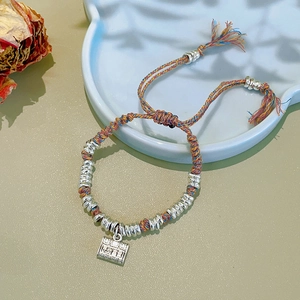 Detailed macro view of handcrafted colorful woven bracelet with silver square pendant