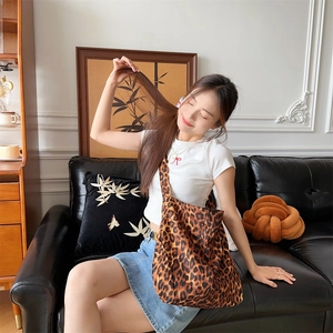 Detailed view of leopard print canvas tote bag being carried by a seated model