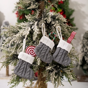 Detailed view of three grey and white knitted Christmas stockings on a snowy pine tree