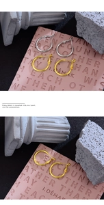 Detail showing elegant gold and silver large hoop earrings on a decorative pink background