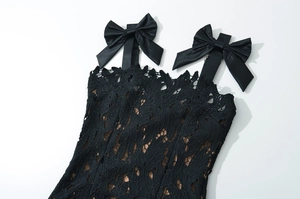 Detailed view of black lace top featuring elegant satin bow straps and floral patterns