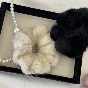 Detail of plush faux fur hair ties in beige and black with decorative pearl chain