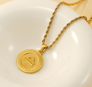 Detailed macro of Libra zodiac coin pendant and gold twist rope chain necklace