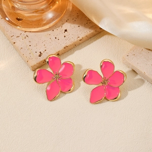 Pink enamel five-petal flower earrings with gold-tone metal trim on stone surface