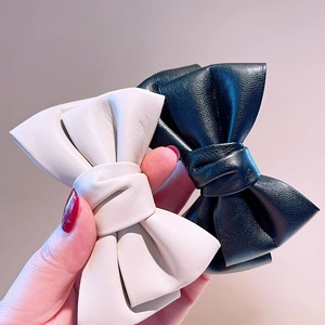 Détail de la texture en cuir et des coutures sur les pinces à nœud noires et crème