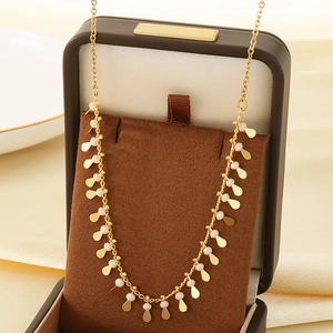 Golden drop tassel necklace with white beads displayed in a premium leather gift box