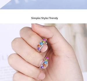 Close-up of small huggie earrings with five colorful rainbow cubic zirconia stones