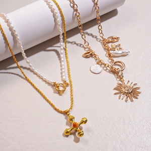 Detail of layered freshwater pearl necklace with gold cross and sun face pendants