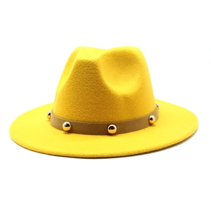 Close-up of a yellow fedora hat with a brown faux leather band and gold metal studs
