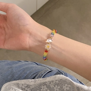 Primer plano de una pulsera de cuentas coloridas con dije de flor en la muñeca de una mujer