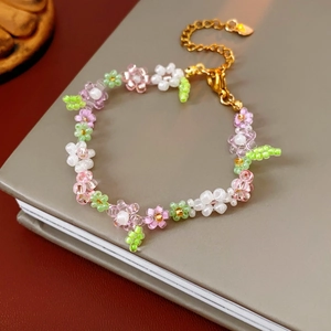 Detail of handmade flower beaded bracelet with pink, white, and green beads and gold clasp