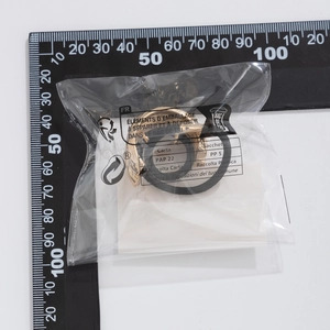 Close-up of golden geometric metal hair tie inside eco-friendly packaging with ruler