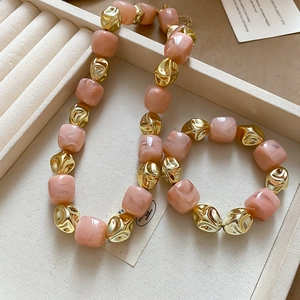 Detailed shot of irregular gold and pink marble beads on a velvet jewelry display tray