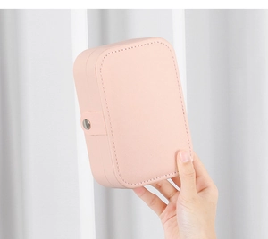 Handheld view of a compact pink PU leather jewelry box featuring a secure metal buckle