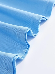 Vue macro du tissu en maille piquée bleu ciel montrant la texture alvéolée du polo pour hommes