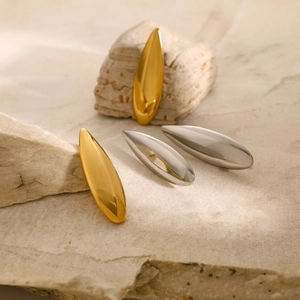 Sleek 18K gold and silver waterdrop earrings displayed on natural textured stone