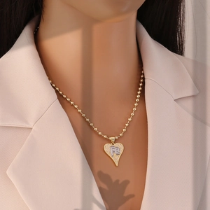 Detail of gold heart pendant with FE silver initials and pavé zircon stones on bead chain