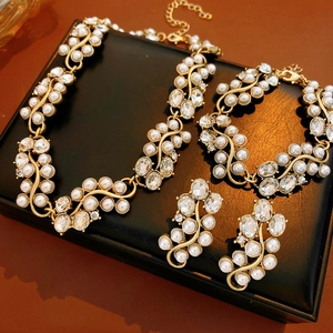 Detail view of gold vintage leaf jewelry set with pearls and crystals on black leather