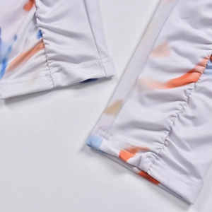 Close-up of ruched cuffs featuring a vibrant orange and blue tie-dye print on soft fabric