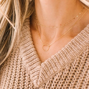 Close-up of double-layer gold stainless steel necklace with circular pendant on a model