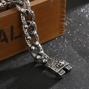 Detail of silver skull link bracelet draped over a wooden box with a punk retro aesthetic