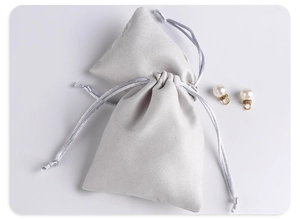 Detailed view of grey microfiber suede drawstring jewelry pouches with pearl earrings
