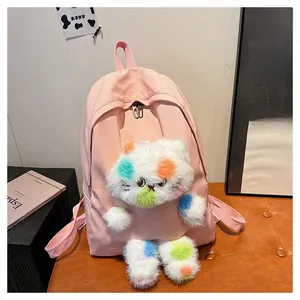 Dettaglio dello zaino in nylon rosa con peluche di gatto bianco su uno sgabello