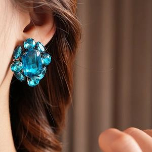 Gros plan de boucles d'oreilles vintage en cristal bleu portées par un mannequin chic