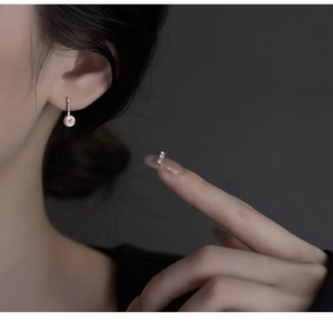 Macro detail of a pink-purple pearl earring on a minimalist S925 silver hook accessory