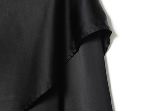 Macro shot of smooth black satin fabric texture with fine stitching on a French style top