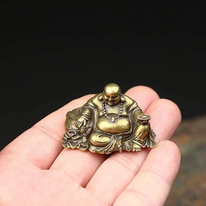 Detailed close-up of a mini brass Laughing Buddha figurine held in hand for scale