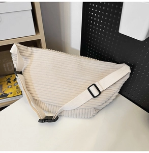 Close-up of beige corduroy crossbody bag texture with adjustable strap and buckle