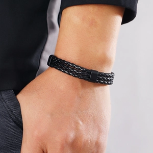 Close-up of a multi-layer black braided leather bracelet with a sleek metal clasp on wrist