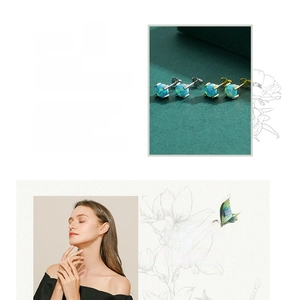 Detailed view of silver and gold opal stud earrings with model on green background
