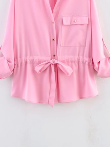 Detail of pink long-sleeve shirt featuring golden buttons and drawstring waist tie