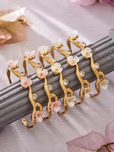 Detail of vintage gold-plated C-shaped flower bracelets with resin petals and crystals