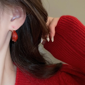 Gros plan de la boucle d'oreille en U plaquée or 14K avec goutte d'émail rouge foncé