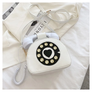 Detailed top view of a white vintage telephone shaped crossbody bag on a blazer
