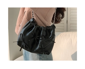 Detail of black PU leather bag with decorative 3D bows and silver metal chain strap