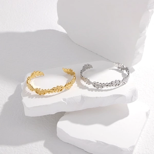 Dettaglio di bracciali aperti a forma di foglia in oro e argento su blocchi di pietra