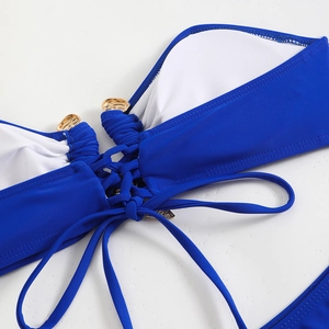 Détail du haut de bikini bleu marine avec lacets croisés et ornements en métal doré