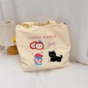 Detail of cute cat embroidery and towel embroidery on beige canvas tote bag surface