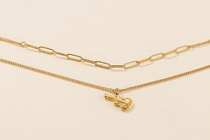 Detail of double-layered gold guitar necklace with thick rectangular links and bass pendant