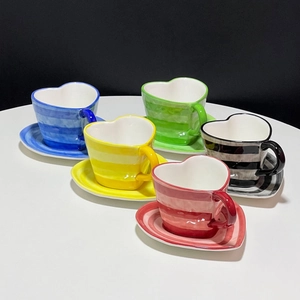 Set of five heart-shaped ceramic coffee cups and saucers in vibrant hand-painted stripes